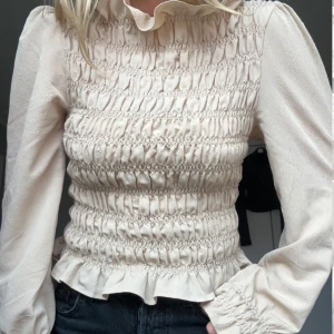 Beige blus med volang - Beige blus med volangkant nedtill och långa puffärmar. Från H&M i storlek S. Fint skick!!