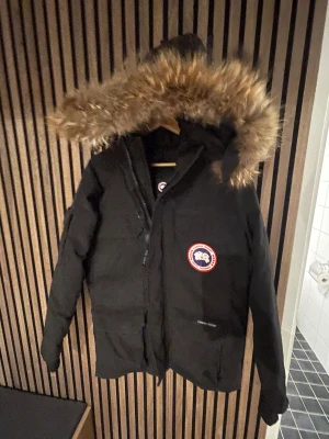 canada goose expedition parka storlek S/M - Säljer en svart Canada Goose Expedition dunjacka med stor huva och fluffig pälsdetalj. Jackan har klassisk patch på bröstet, flera fickor och dragkedja framtill. Perfekt för kalla vinterdagar och har en riktigt schysst oversized look. 