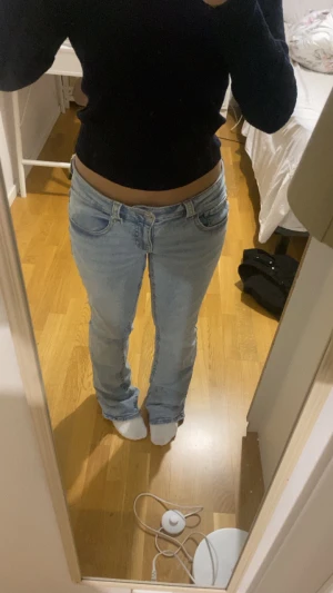 Bootcut ljusblå jeans från Perfect Jeans - Säljer ett par ljusblå bootcut jeans från Perfect Jeans i storlek 40. De har låg midja, klassiska fem fickor och snygga detaljer med knappar på bakfickorna. Jeansen är tillverkade i jeansmaterial och har en chill passform med lite utsvängda ben.