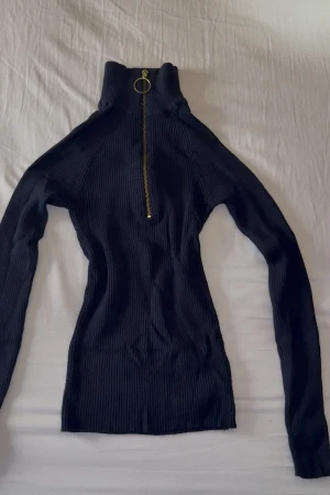 Polotröja GinaTricot  - Marinblå tröja med polokrage ifrån Gina Tricot. Mässingfärgad dragkedja, tight modell. Storlek XS, knappt använd. 