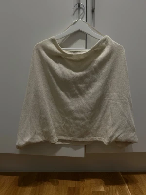 Off-shoulder tröja - Säljer en beige topp med loose passform, tillverkad i mjukt bomullsmaterial. Toppen är enkel och stilren utan mönster eller detaljer, och har en lätt och luftig känsla. Perfekt för dig som gillar minimalistisk stil och bekväma plagg.