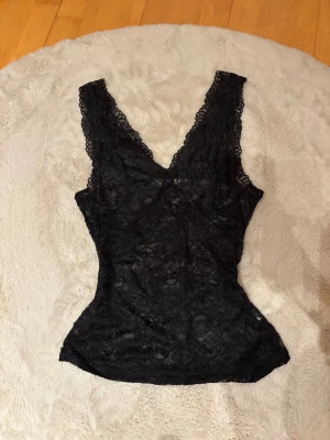 Svart spetslinne  - Svart figurnära spetstopp från cream i storlek S