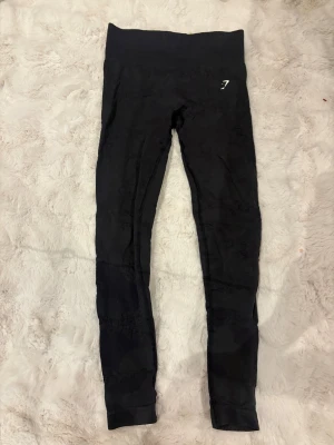 Svarta leggings från Gymshark - Svarta leggings från Gymshark med hög midja och diskret logga på vänster höft. Stretchigt syntetmaterial som sitter tight och formar benen. 