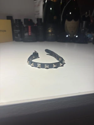 Valentino Garavani svart läderarmband - Svart läderarmband från Valentino Garavani med silverfärgade spikar plus justerbart spänne. Någolunda slitet men inget märkbart. Tyvärr inget og. 