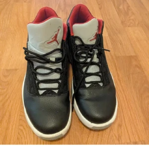 Svarta Nike Jordan sneakers - Säljer ett par svarta Nike Jordan sneakers med vit sula och röda detaljer på insidan och tungan. Skorna har snörning och är tillverkade i skinn och mesh för en cool och sportig look. Jumpman-loggan syns tydligt på tungan.