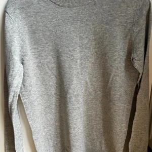 Grå tröja från H&M - En stilren grå långärmad tröja från H&M. Tröjan har rund halsringning. Perfekt för lager-på-lager och enkel att matcha med olika outfits. Skulle säga att den är i storlek M/S. Skriv ifall ni vill se fler bilder av tröjan eller om ni vill se den på!💕 
