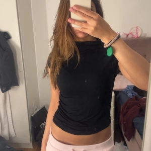 Svart croppad topp med hög hals - Svart croppad topp med hög hals och korta ärmar. Sitter tight och har en enkel, stilren look. Perfekt att matcha med jeans eller kjol. Gjord i mjukt och stretchigt material som känns skönt mot huden. Priset kan diskuteras 