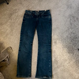 Blå bootcut jeans från LTB Valerie - Snygga blå jeans från LTB, modellen Valerie. Bootcut passform med klassisk femficksdesign och dragkedja. Jeansen har en mörkblå tvätt och är tillverkade i jeansmaterial med skön stretch. Perfekt för dig som gillar en tidlös look med lite utsvängda ben.