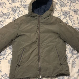 Colmar Jacka - Säljer en grön dunjacka från Colmar med blått quiltat foder. Jackan har huva, två snedställda fickor med dragkedja och hel dragkedja framtill. Perfekt för kalla dagar och har en clean look. Jackan är fodrad och är i fint skick! Den passar S som bäst, pris går att diskutera🙌