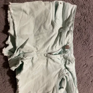 Ljusblåa jeansshorts från Esmara - Säljer ett par ljusblåa jeansshorts från Esmara i storlek 36. De har råa, fransiga benslut, klassisk femficksdesign och dragkedja med knapp. Perfekta för varma dagar och har en modern straight fit.
