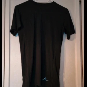 Svart tränings t-shirt från Ronhill - En stilren svart t-shirt från Ronhill med diskret logga nedtill. Klassisk passform med rund hals och korta ärmar. Perfekt för dig som gillar enkel och sportig stil. Materialet känns mjukt och lätt mot huden.