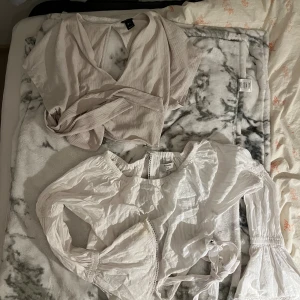 Ljusa toppar  - Säljer två snygga toppar,  Ena är en ljusbeige omlottopp med korta ärmar och ribbad struktur, den andra är en vit blus med långa puffärmar, spetsdetaljer och knyt i midjan. 
