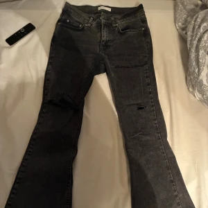 Svarta bootcut jeans med slitningar - Low waisted jeans med självklippta hål. Storlek 34 och jeansen e från Gina tricot💕