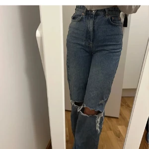 Blå ripped jeans från g perfect jeans - Säljer ett par blå jeans från g perfect jeans i storlek 32. De är högmidjade med raka ben och har stora slitningar vid knäna för en cool, avslappnad look. Klassisk denim med orange sömmar och femficksmodell. Knappt använda 