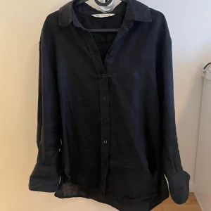 Svart linneskjorta från Zara - Svart skjorta från Zara i mjukt linne med klassisk krage och knappar framtill. Skjortan har lång ärm och en loose passform.