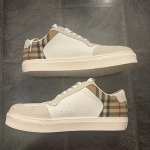 Vita burberry skor - Snygga vita sneakers från Burberry. Det är en materialmix av skinn och mocka ger en lyxig känsla och den rutiga designen gör dem riktigt unika. De är i storlek 46 och är knappt använda 🙌