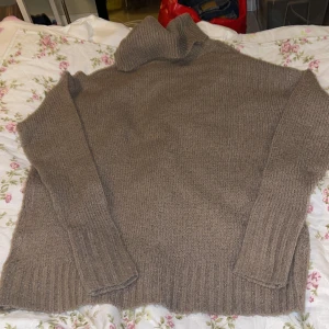 Brun  stickad polotröja - Mysig brun stickad polotröja med bred krage och ribbade muddar vid ärmslut och nederkant. Tröjan har en loose passform och är perfekt för kyliga dagar. Materialet är mjukt och ger en chill vibe, enkel att styla med jeans eller leggings.