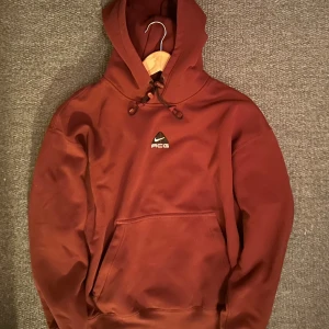 Brun Nike ACG hoodie Therma-Fit M - Säljer en röd Nike ACG hoodie i Therma-Fit material. Tillverkad i en mjuk bomulls- och polyestermix som håller dig varm. Perfekt för höst och vinter. Tveka inte att meddela vid funderingar🙌