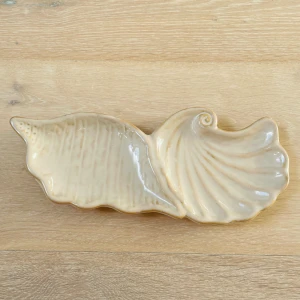 Bricka skalform - En ny bricka i snäckform. Perfekt som förvaring i badrummet – till exempel för tvålar eller dina smycken. Designen i form av ett snäckskal ger ett elegant och genomtänkt intryck.
 Storlek: bredd 10 cm, längd 25 cm, höjd 2 cm.
 Tillgänglig för upphämtning i Kista, Stockholm, eller leverans
 