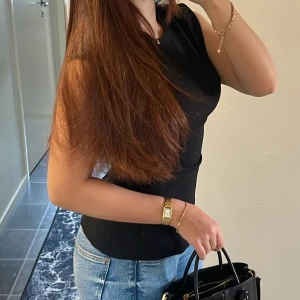 Svart ärmlös topp från Zara  - Säljer en stilren svart topp med rund hals och ärmlös design. Toppen har en figurnära passform och är tillverkad i ett mjukt, stretchigt material som sitter snyggt på kroppen. Perfekt att matcha med jeans eller kjol för en clean look.