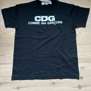 CDG T shirt - Svart t-shirt från Comme des Garçons med stor vit CDG-logga på bröstet. Nyskick!