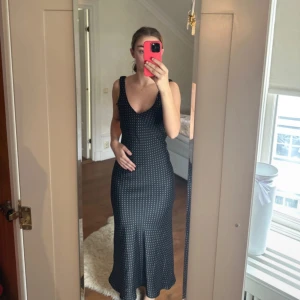 Svart prickig långklänning med v-ringning - Supersnygg svart långklänning med vita prickar och v-ringad hals. Klänningen är ärmlös med breda axelband och har en lätt utsvängd nederdel som ger en fin siluett. Materialet känns mjukt och följsamt, perfekt för dig som gillar en klassisk men trendig look. Jag är 167cm lång och den går ner till min vad, för mer info skriv☺️. Köpte från Zara för cirka 1 år sen och den har inte kommit till användning efter dess. Använde endast vid köp i butik ‼️