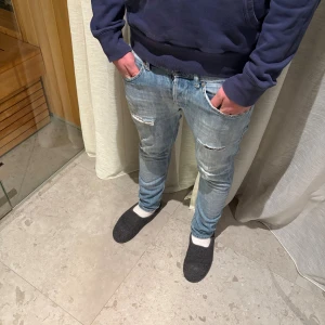 Dondup jeans - Säljer ett par ljusblå jeans från dondup med snygga slitningar och trasiga detaljer på både fram- och baksidan. Modellen har smal passform och klassisk femficksdesign. Perfekt för dig som gillar en avslappnad streetstil.