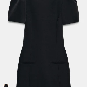 Svart kort klänning från Zara slutsåld  - Stilren svart kort klänning från Zara med markerade axlar och korta ärmar. Klänningen har en figurnära passform och diskreta fickdetaljer framtill. Perfekt för dig som gillar minimalistisk och elegant stil.