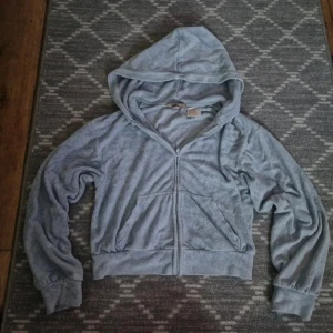 Ljusblå velour hoodie med dragkedja - Mysig ljusblå hoodie i mjuk velour med dragkedja framtill och huva. Tröjan har långa ärmar, ribbade muddar och två fickor framtill. Perfekt för en chill och avslappnad stil.