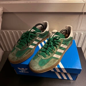 Adidas Samba OG gröna sneakers - Adidas Samba OG sneakers i grön mocka och skinn med vita detaljer och klassiska tre ränder på sidan. Gummisula med mönster och gröna skosnören. Perfekt för dig som gillar retrostil och streetwear. Storlek 42 (EU), 8,5 (US).