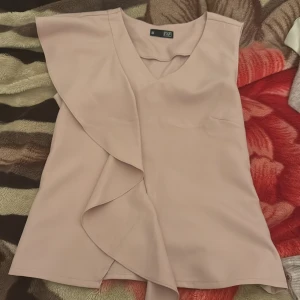 Ljusrosa blus med volang från F&F - Jättefin ljusrosa top/blus med volang. Har använt den 2 gånger, och säljer den för 75kr