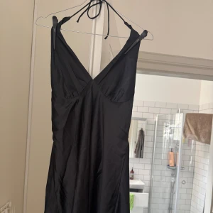 Svart halterneckklänning - Svart miniklänning med halter top. Satin-liknande material. Aldrig använd. Ordnar självklart fler bilder på klänningen om det önskas😊 