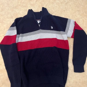 Randig stickad tröja från U.S. Polo Assn. - Mörkblå stickad tröja från U.S. Polo Assn. Tröjan är half zip den är använd några gånger. Den är L men passar som M också.                                     Jag köpte den för 900 kr