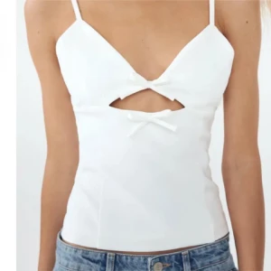 Vit topp med rosetter - Säljer denna söta topp med rosetter från Zara. Sällan använd så är i jättebra skick. Formas jättefint på kroppen🤍