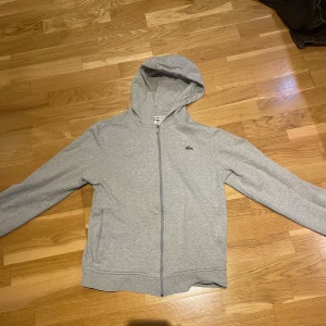 Grå Snygg Lacoste zip tröja  - Grå Lacoste zip up tröja i storlek medium, ganska liten i storlek och är i bra skick 