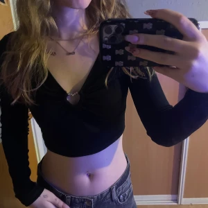 Svart croppad långärmad topp  - Säljer en svart croppad långärmad topp med djup v-ringning med ett fint hjärta framtill. Toppen är ribbad! 