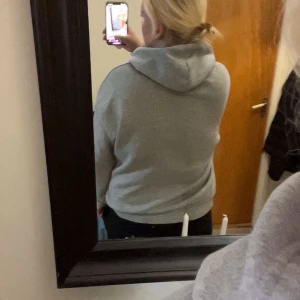 Grå zip-hoodie med huva - Säljer en klassisk grå hoodie med dragkedja och huva. Tröjan har snörning i huvan, två fickor framtill och ribbade muddar vid ärmslut och nederkant. Perfekt för chill dagar eller när du vill ha något bekvämt och stilrent.