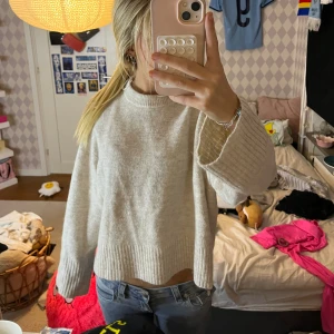 Beige stickad tröja från Gina Tricot - Mysig beige stickad tröja från Gina Tricot med rund halsringning och breda ribbade muddar vid ärmslut och nederkant. Tröjan har en loose passform och är perfekt för lager-på-lager-stil under kyliga dagar.