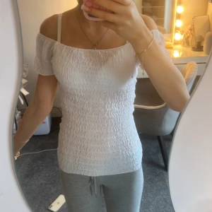 Vit offshoulder topp från Zara - Supersöt vit offshoulder topp från Zara i storlek S. Toppen har en smockad struktur med vågigt mönster och korta ärmar.  Materialet känns lätt och luftigt.