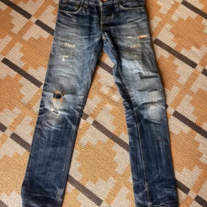 Nudie jeans - Grim Tim Dry Selvage (Unisex) - Edition jeans från Nudie- som nya! Nypris 3000 kr.  Storlek 28/32  Unisex  Nudie Grim Tim Dry Selvage Raw Denim Jeans Fabric: 100% organic cotton selvedge denim Fabric source: Japan Made in: Italy Fit: Slim  https://www.instagram.com/p/CeIpVGYPF8P/ w