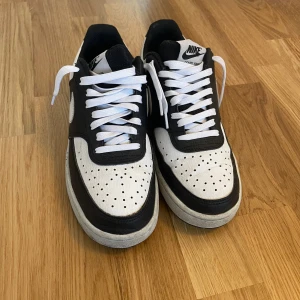 Nike svartvita sneakers - Svartvita Nike sneakers i klassisk low-modell. Skorna har vit bas med svarta paneler, vit swoosh och vita skosnören. Nästan aldrig använda. Kostar från början runt 800😊