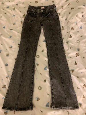 Svarta low waist bootcut jeans från Nelly - Snygga svarta bootcut jeans från Nelly med markerade sömmar framtill och stora fickor. Dom är lowwaist och i stolen 34. 