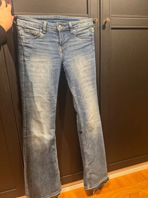 Blå lågmidjade bootcut jeans  - Säljer ett par blå jeans med bootcut passform. Jeansen är lågmidjade och sitter väldigt bra runt midjan. Perfekta för en avslappnad och trendig look. Köpta i USA från H&M.