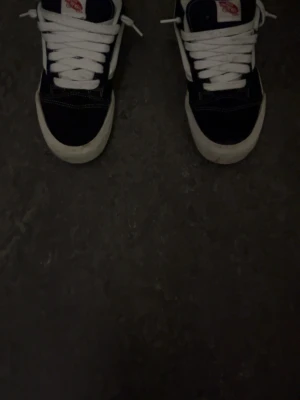 Svarta och vita Vans Old Skool sneakers - Klassiska Vans Old Skool sneakers i svart och vitt med vit sula och vit sidestripe. Skorna har snörning och tydliga kontrastsömmar. Ovandelen är i mocka och textil, med Vans-logga på plösen. Perfekta för en chill streetstyle-look.