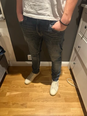 Blå tiger of Sweden jeans - Säljer ett par blå jeans från tiger of Sweden i storlek 31/30. Jeansen har klassisk femficksdesign, raka ben och snygga slitningar framtill. Materialet är tåligt jeans och passformen är normal. 