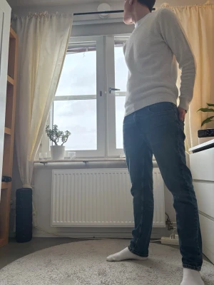 Vit stickad tröja med strukturmönster - Säljer en vit stickad tröja med diskret strukturmönster. Tröjan har rund hals, långa ärmar och ribbade muddar vid ärmslut och nederkant. Passformen är normal och materialet känns mjukt och bekvämt, perfekt för kyligare dagar.