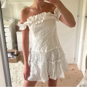 Vit offshoulder klänning med volang från Zara - Klänning från Zara. Pris kan diskuteras!Supersöt vit kortklänning med offshoulder och volangkant. Klänningen har broderade detaljer och flera lager med rynkade volanger. Perfekt för sommarens alla tillfällen! Storlek S