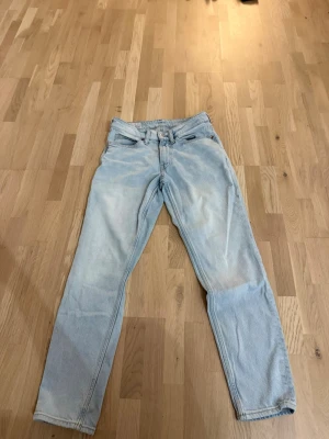 Ljusblå jeans  - Säljer ett par ljusblå jeans från H&M med regular tapered passform. Klassisk femficksmodell med normal midja och raka ben som smalnar av nedtill. Tillverkade i mjukt bomullsmaterial, perfekta för en avslappnad stil.