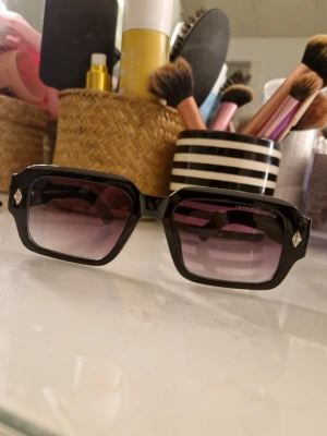 Svart/lila Chrome Hearts glasögon - Säljer ett par svarta glasögon med lila glas från Chrome Hearts med feta silvriga detaljer på sidorna. Perfekt för dig som vill sticka ut med exklusiva detaljer och edgy look. Perfekt för sommar o våren, pris kan diskuteras vid smidig affär