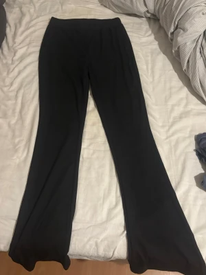 Svarta ribbade byxor  - Svarta ribbade byxor från SHEIN med hög midja och utsvängda ben. Byxorna är stretchiga och har en mjuk känsla, perfekta för en chill och trendig look. Passar dig som gillar bekväma men ändå snygga byxor.